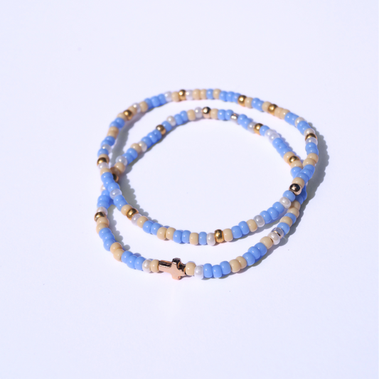 Beaded bracelet with blue, gold, and beige beads on a light purple background