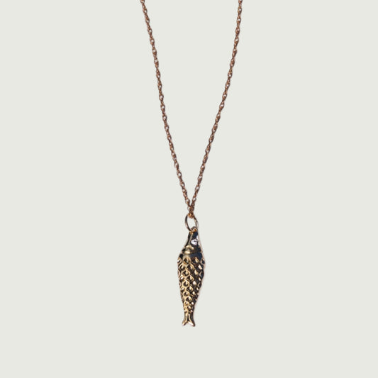 Gold fish-shaped pendant on a chain against a white background