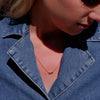 Close-up of a person wearing a blue denim jacket with a necklace.
