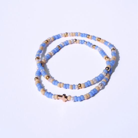 Beaded bracelet with blue, gold, and beige beads on a light purple background