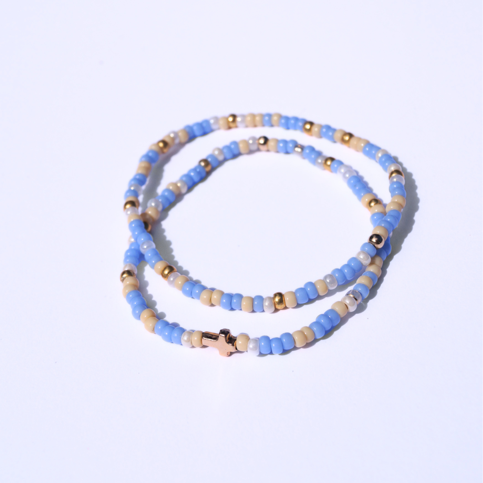 Beaded bracelet with blue, gold, and beige beads on a light purple background