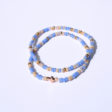 Beaded bracelet with blue, gold, and beige beads on a light purple background