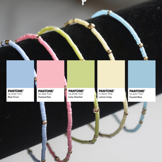 Set of colorful bracelets on a black stand with Pantone color swatches below with pastel colorways. 