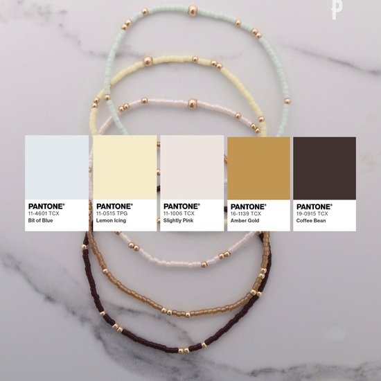 Three layered bracelets with color swatches labeled Pantone on a marble background