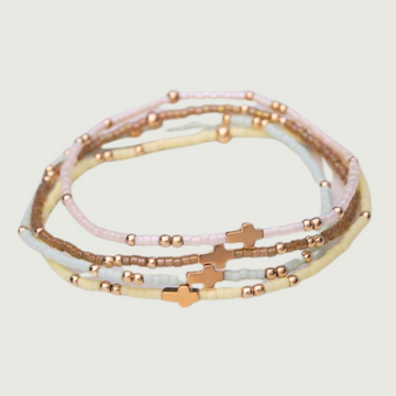 Set of three beaded bracelets with cross charms on a light gray background