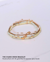 Stack of beaded bracelets with gold cross and accents on a light gray background