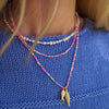 Close-up of a person wearing multiple beaded necklaces with a blue sweater.