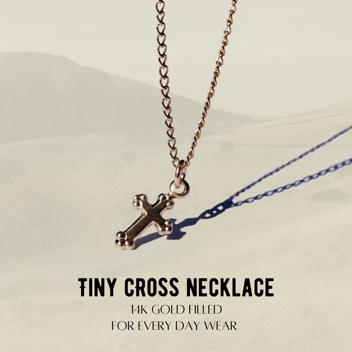 Tiny Cross Necklace, 14k gold-filled cross charm on a beige background
