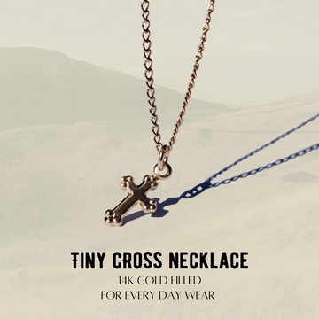 Tiny cross necklace with gold filling on a beige background