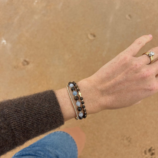 Aquamarine and Bronzite Beaded Bracelet stacked on the wrist above the sand at the beach