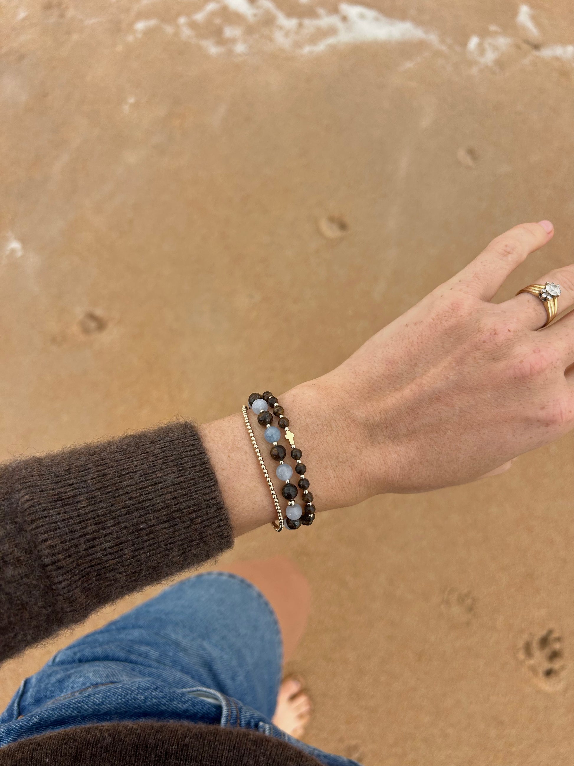 Aquamarine and Bronzite Beaded Bracelet stacked on the wrist above the sand at the beach