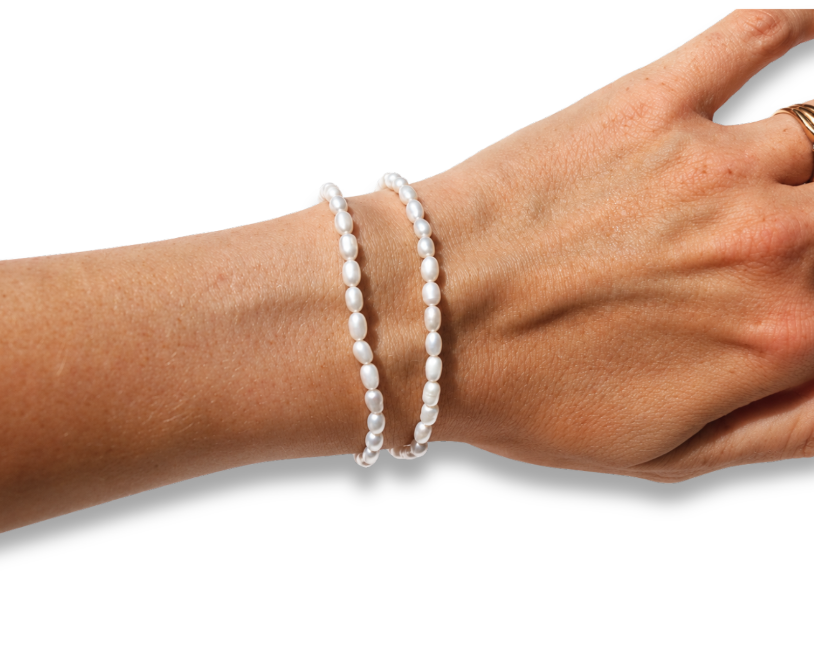 Two white pearl beaded bracelets on a person's wrist, shown against a plain white background with a gold ring visible on the finger.
