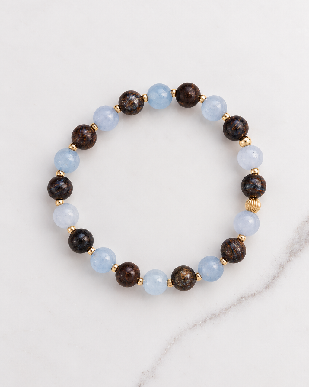 Aquamarine and Bronzite Beaded Bracelet in gold, laid flat on white marble