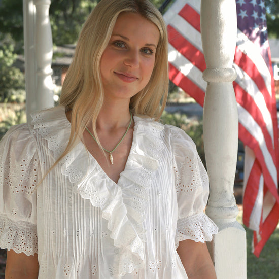 Woman in a white blouse standing in front of an American flag