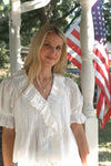 Woman in a white blouse standing in front of an American flag