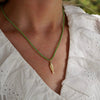 Close-up of a person wearing a green beaded necklace with a delicate pendant.
